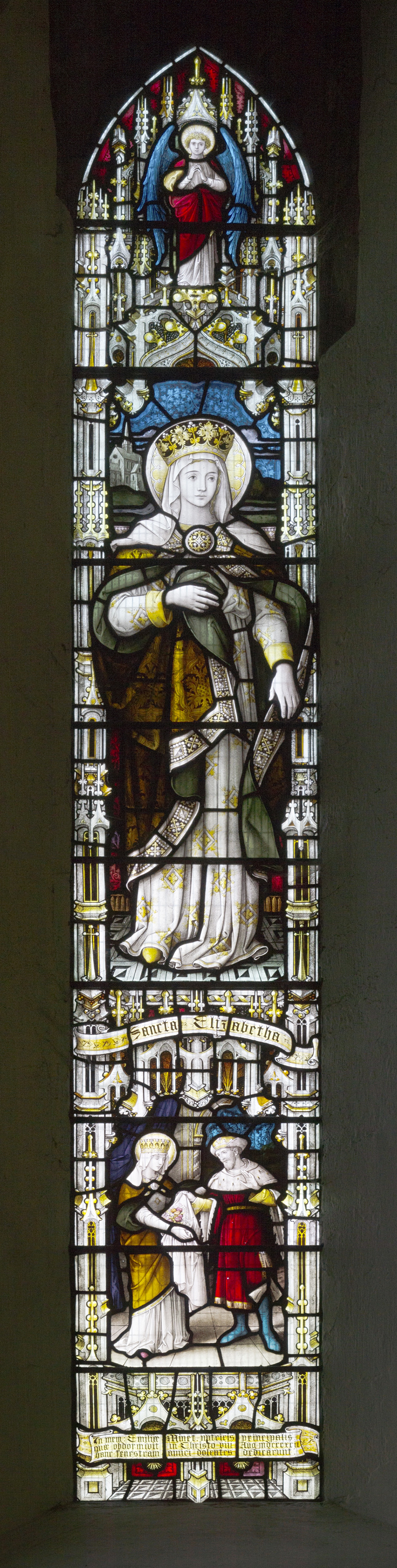 Stained glass window depicting a haloed figure in robes holding a staff, with smaller figures below and intricate architectural details, all in vibrant colours.