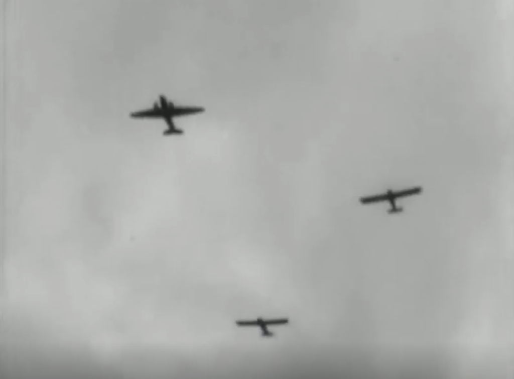 Four aeroplanes are flying in formation against a cloudy sky, viewed from below in a black and white image.