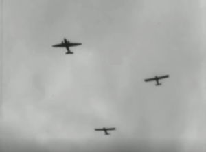 Four aeroplanes are flying in formation against a cloudy sky, viewed from below in a black and white image.